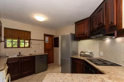 a kitchen with wooden cabinets and a stainless steel refrigerator at Kruger Park Lodge Unit No. 216 in Hazyview