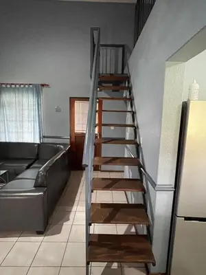 a wooden staircase in a living room with a couch at Pendleberry Grove Unit 51 in Bela-Bela
