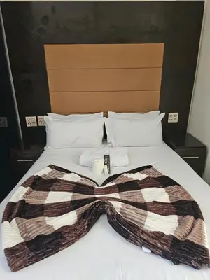 a bed with a blanket and a candle on it at DBright Lodge in Pretoria