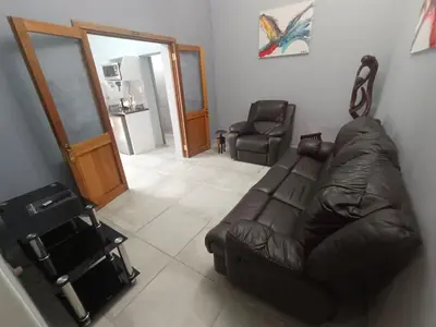 a living room with a leather couch and two chairs at Clyde's on Dale Guest House in Springs