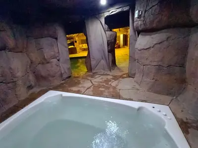 a bath tub in a room with a stone wall at Clyde's on Dale Guest House in Springs