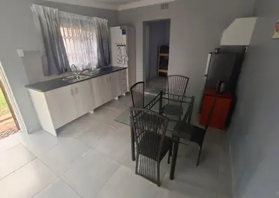 a kitchen with a table and chairs and a refrigerator at Clyde's on Dale Guest House in Springs