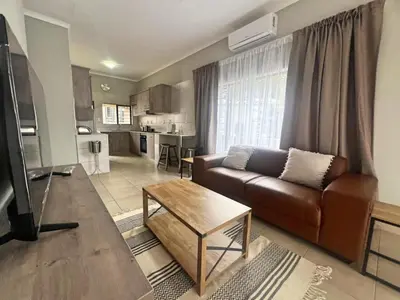 a living room with a brown couch and a table at Vaendzi Lodge in Nelspruit