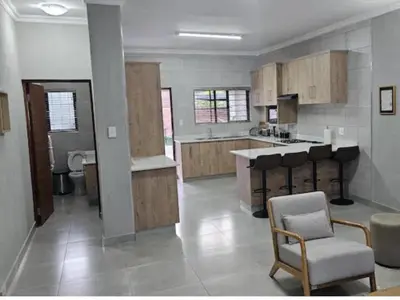 a large kitchen with wooden cabinets and a chair at Vaendzi Lodge in Nelspruit