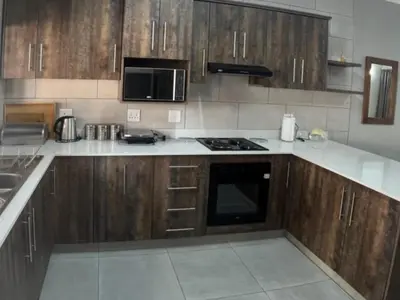 a kitchen with wooden cabinets and a stove top oven at Vaendzi Lodge in Nelspruit