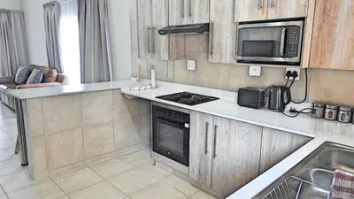 a kitchen with a stove and a microwave at Vaendzi Lodge in Nelspruit