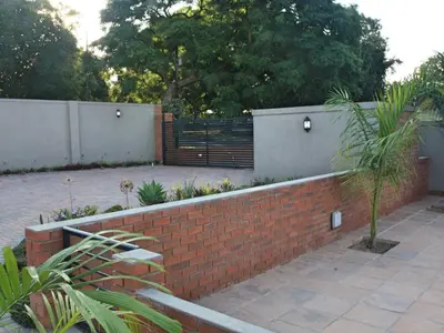 a brick retaining wall with a fence and plants at Vaendzi Lodge in Nelspruit