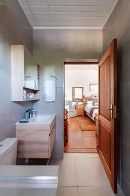 a bathroom with a sink and a toilet and a bedroom at House Falcon in Pretoria
