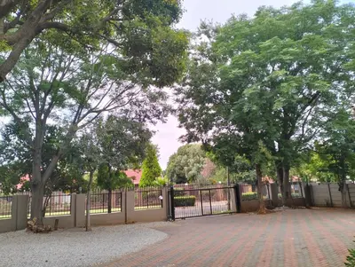 a fence with trees in front of a park at O&S BnB in Centurion