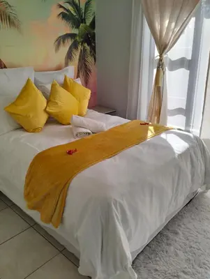 a white bed with yellow pillows and a blanket on it at O&S BnB in Centurion