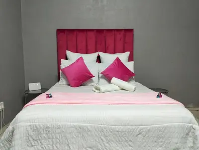 a large bed with pink pillows and a red headboard at O&S BnB in Centurion