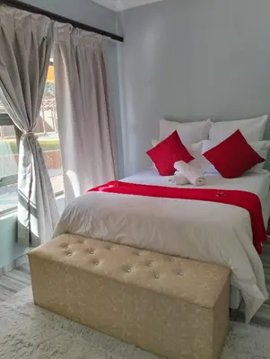 a bedroom with a large bed with red pillows at O&S BnB in Centurion