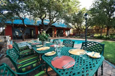 a green table with chairs and a table with plates and glasses at Mohlabetsi Self Catering Bush Lodge in Balule Game Reserve