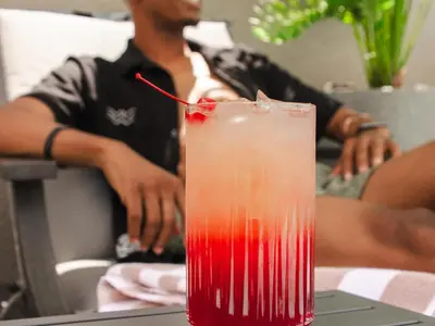 a red drink sitting on a table with a man at Q's Evander Hotel & Apartments in Evander