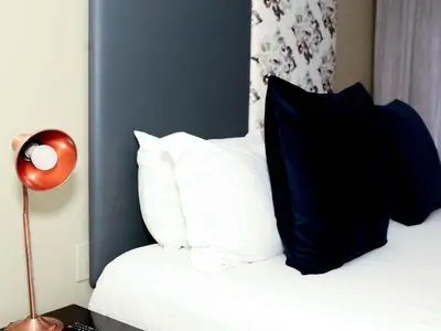 a bed with black and white pillows and a lamp at Q's Evander Hotel & Apartments in Evander