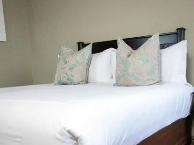 a bed with white sheets and pillows at Q's Evander Hotel & Apartments in Evander