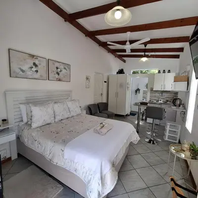 a bedroom with a large bed and a kitchen at Sleep Haven Self-Catering Accommodation - Nelspruit in Nelspruit