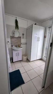 a white bathroom with a sink and a white tiled floor at Sleep Haven Self-Catering Accommodation - Nelspruit in Nelspruit