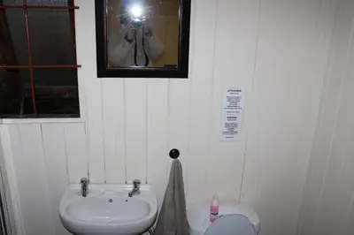 a person taking a picture of a bathroom with a sink at Magoebaskloof Getaway in Magoebaskloof