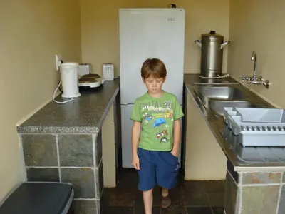 a young boy standing in a bathroom next to a sink at Magoebaskloof Getaway in Magoebaskloof
