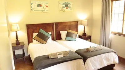 two beds in a bedroom with two lamps and two beds at Magoebaskloof Getaway in Magoebaskloof