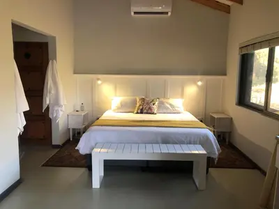 a bedroom with a bed with a bench in it at Modern Bush Living in Marloth Park