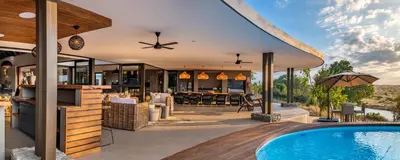 an outdoor patio with a swimming pool and a house at Marula Sunrise Lodge, Mjejane Private Game Reserve in Hectorspruit