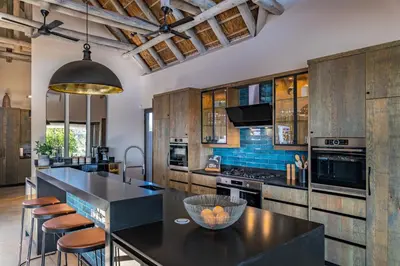 a kitchen with wooden cabinets and a black counter top at Marula Sunrise Lodge, Mjejane Private Game Reserve in Hectorspruit