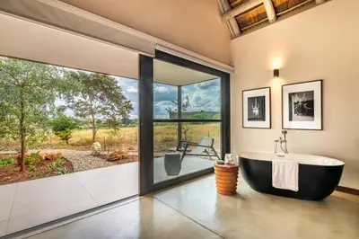 a bathroom with a tub and a large window at Marula Sunrise Lodge, Mjejane Private Game Reserve in Hectorspruit