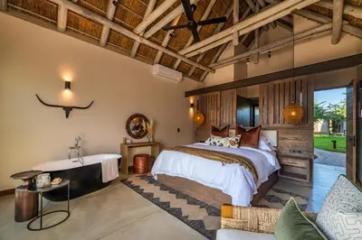 a bedroom with a large bed and a tub at Marula Sunrise Lodge, Mjejane Private Game Reserve in Hectorspruit