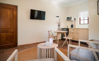 a living room with a tv and a table and chairs at The Lofts @ Maple Square in Dullstroom