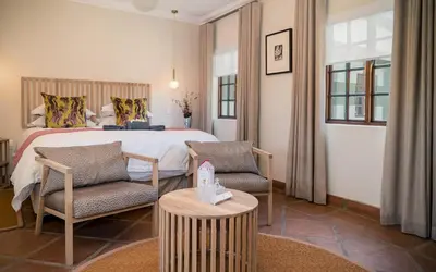 a bedroom with a bed and two chairs and a table at The Lofts @ Maple Square in Dullstroom