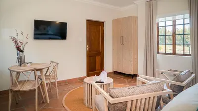 a living room with a table and chairs and a television at The Lofts @ Maple Square in Dullstroom