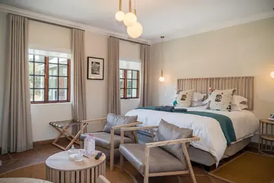 a bedroom with a bed and chairs and a table at The Lofts @ Maple Square in Dullstroom