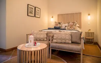 a bedroom with a bed and a chair and a table at The Lofts @ Maple Square in Dullstroom