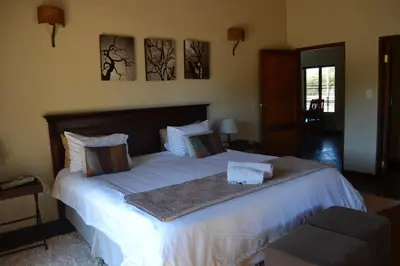 a bedroom with a large bed with white sheets at Makhato 84 Bush Lodge in Bela-Bela