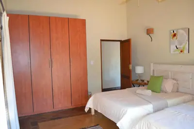 a bedroom with two beds and a large wooden cabinet at Makhato 84 Bush Lodge in Bela-Bela