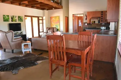 a kitchen and living room with a wooden table and chairs at Makhato 84 Bush Lodge in Bela-Bela