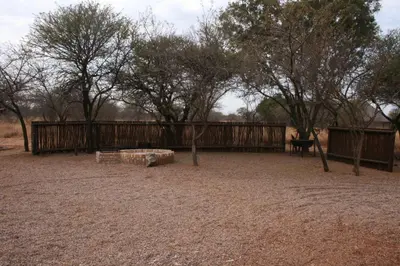 a playground with a wooden fence and trees at Makhato 84 Bush Lodge in Bela-Bela