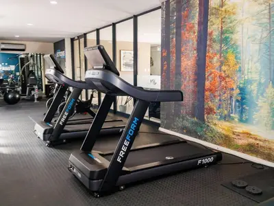 a gym with two treadmills and a flat screen tv at Luminant Escapes -With Power Backup in Midrand