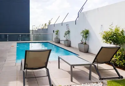 two chairs and a table next to a swimming pool at Luminant Escapes -With Power Backup in Midrand