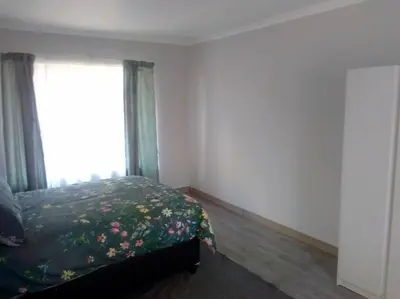 a bedroom with a bed with a floral bedspread and a window at Anglerfish in Centurion
