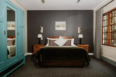 a bedroom with a bed and two lamps and a window at Filmerton Country Lodge in Kyalami