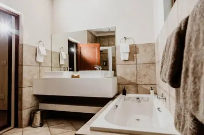 a bathroom with a large tub and a sink at Filmerton Country Lodge in Kyalami