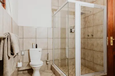 a bathroom with a toilet and a shower at Filmerton Country Lodge in Kyalami