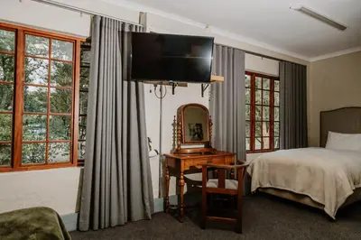 a bedroom with a bed and a television on the wall at Filmerton Country Lodge in Kyalami