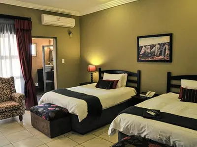 a hotel room with two beds and a chair at 2Ten Hotel in Sibasa