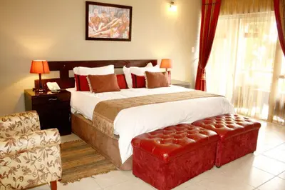 a bedroom with a large bed with a red ottoman at 2Ten Hotel in Sibasa