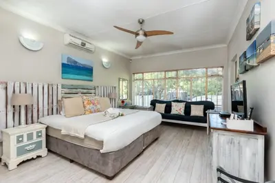 a bedroom with a large bed and a couch at Fralande Self Catering Units in Pretoria