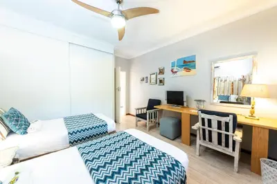 a bedroom with two beds and a desk with a computer at Fralande Self Catering Units in Pretoria